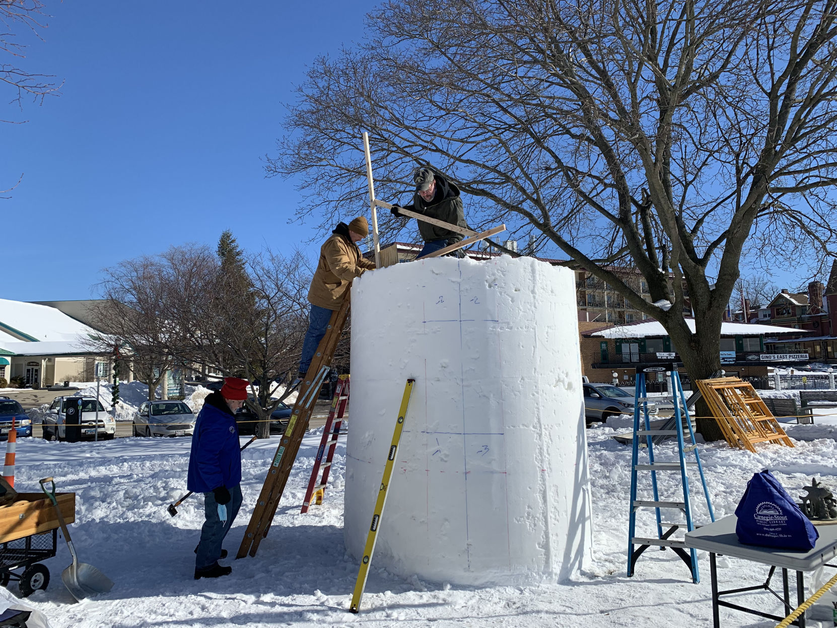 A snow sculpting team measures out their cylinder of snow to begin working on their snowy work of art
